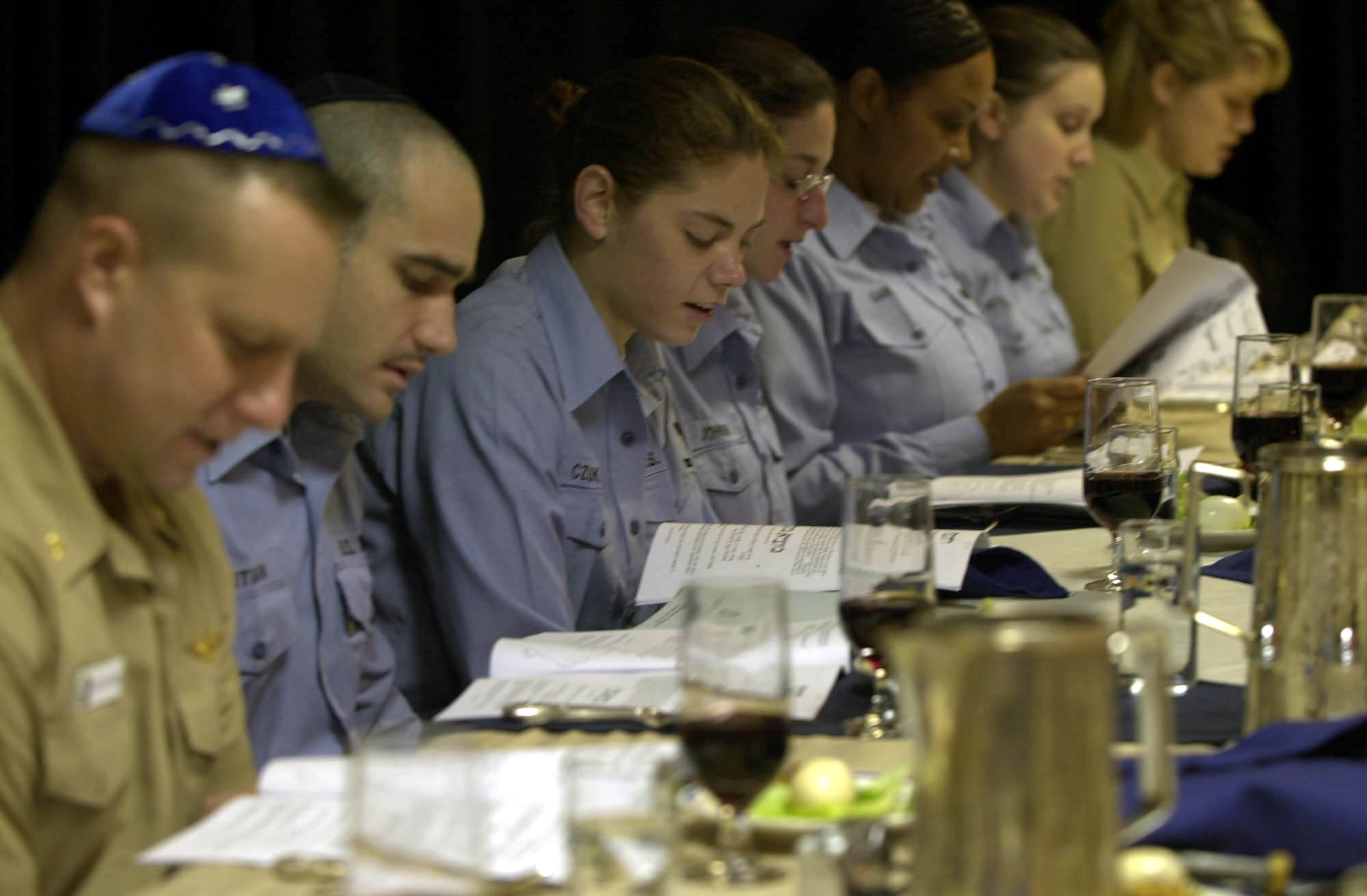 US Navy Crewmembers read from the Passover Hagaddah during the Passover Seder dinner in the wardroom aboard USS Nimitz 